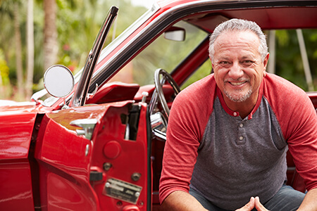 Retired man sitting in restored red mustang